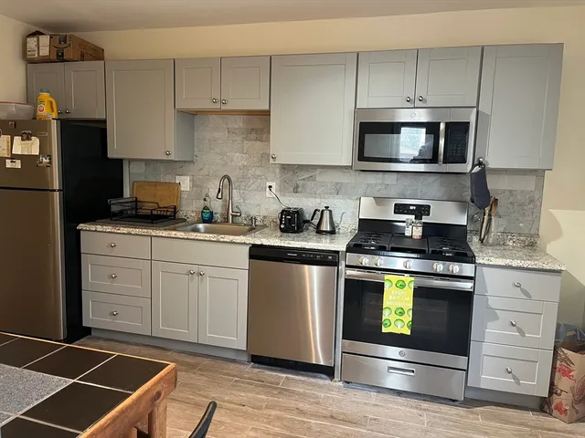 a kitchen with granite countertop white cabinets stainless steel appliances and a sink