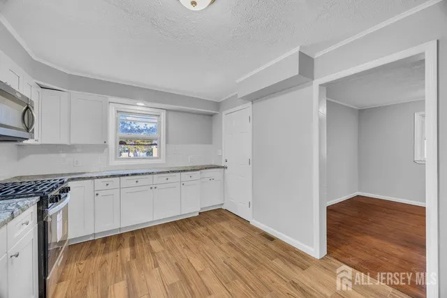 a kitchen with granite countertop white cabinets and wooden floor