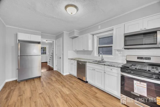 a kitchen with granite countertop wooden floors and stainless steel appliances