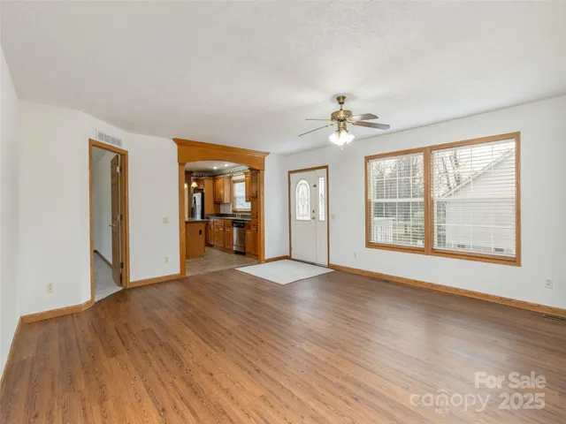 a view of an empty room with a window and wooden floor