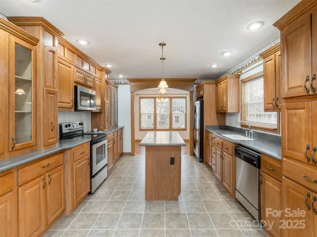 a large kitchen with stainless steel appliances granite countertop a stove and large cabinets