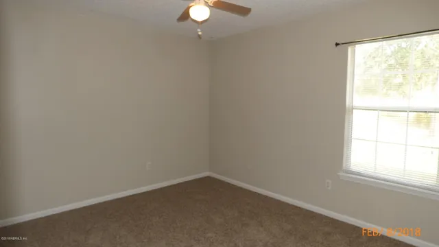 a view of an empty room and chandelier fan and fire place