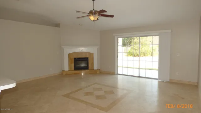 an empty room with windows and fireplace