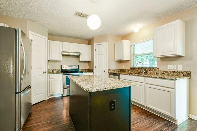 a kitchen with granite countertop white cabinets and white appliances