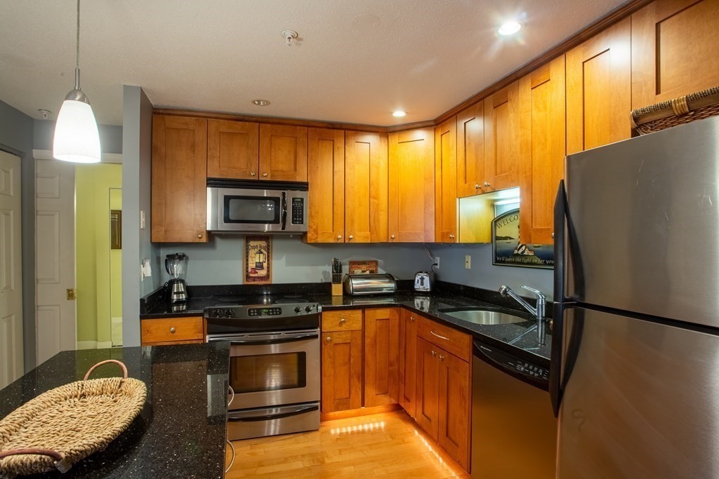 11 Church Street, Unit 101 Salem, MA 01970 - Photo 15 of 31 a kitchen with granite countertop wooden cabinets stainless steel appliances and a window