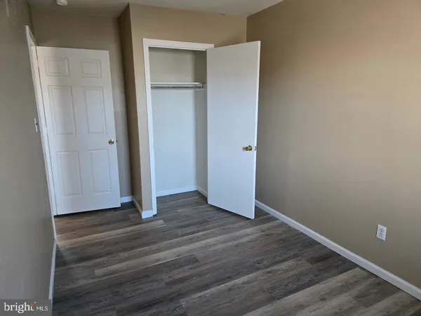 a view of an empty room with closet and wooden floor