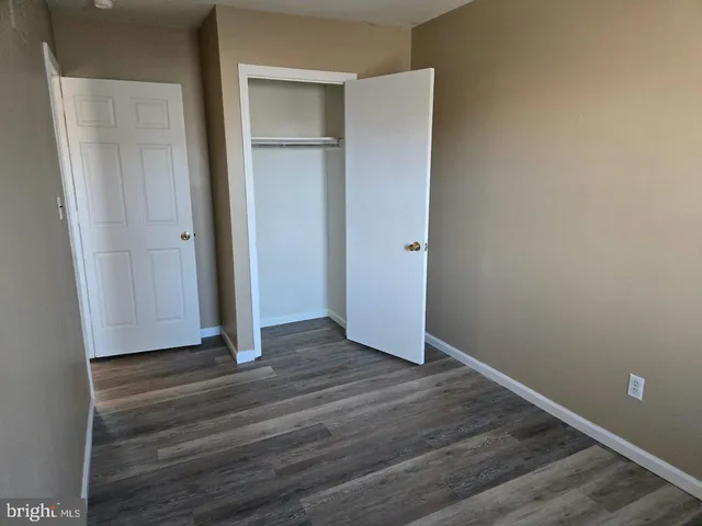 a view of an empty room with closet and wooden floor
