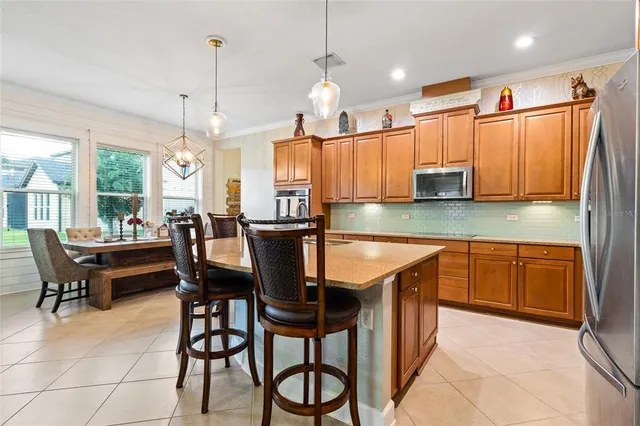 a kitchen with stainless steel appliances granite countertop wooden cabinets a stove a sink a dining table and chairs with wooden floor