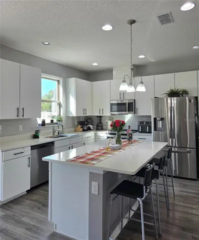 a kitchen that has a lot of cabinets a sink and appliances