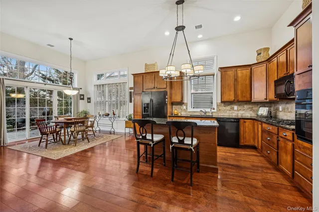 a open kitchen with stainless steel appliances granite countertop a stove a kitchen island a dining table and chairs