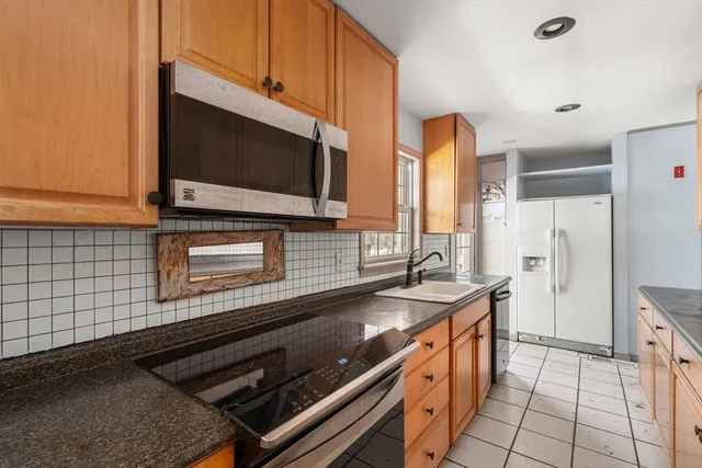 a kitchen with stainless steel appliances kitchen island granite countertop a stove and a microwave