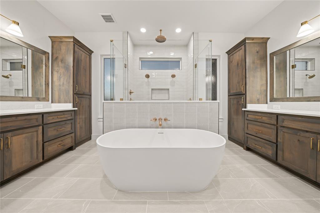 1031 Ranch Vista Road Granbury, TX 76049 - Photo 22 of 32 Freestanding soaking tub, dual vanities with wood-finish cabinetry, frameless glass shower enclosures, and light-toned tile flooring