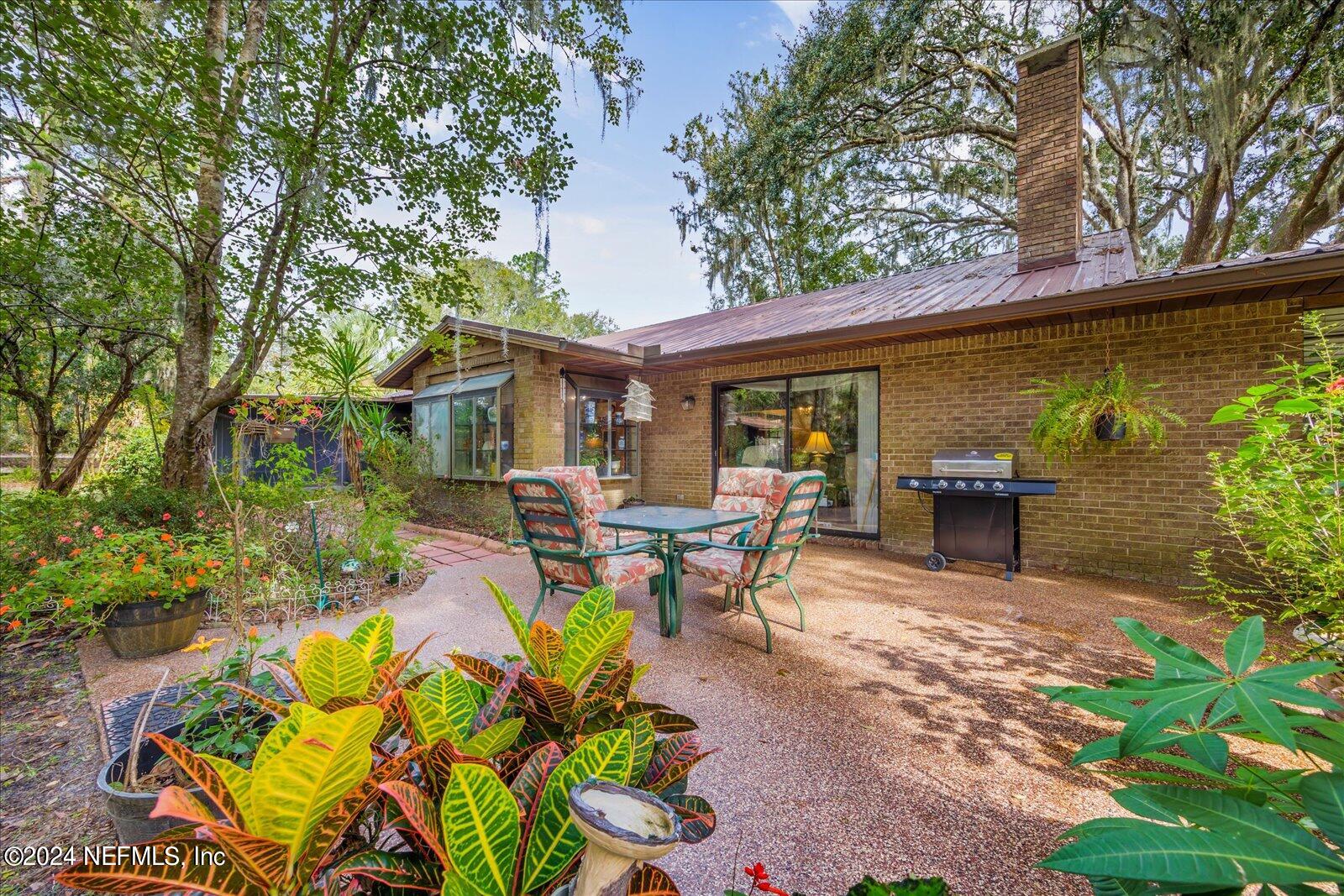 195 Horseman Club Road Palatka, FL 32177 - Photo 43 of 58 a view of a patio with table and chairs potted plants and large tree