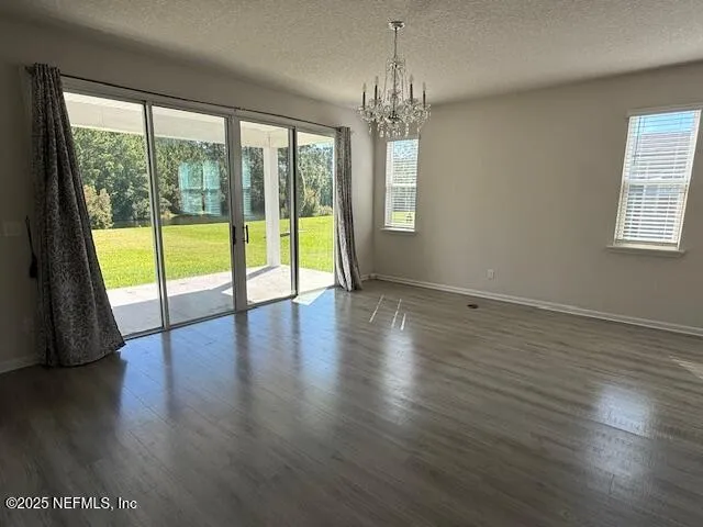 an empty room with wooden floor and large windows