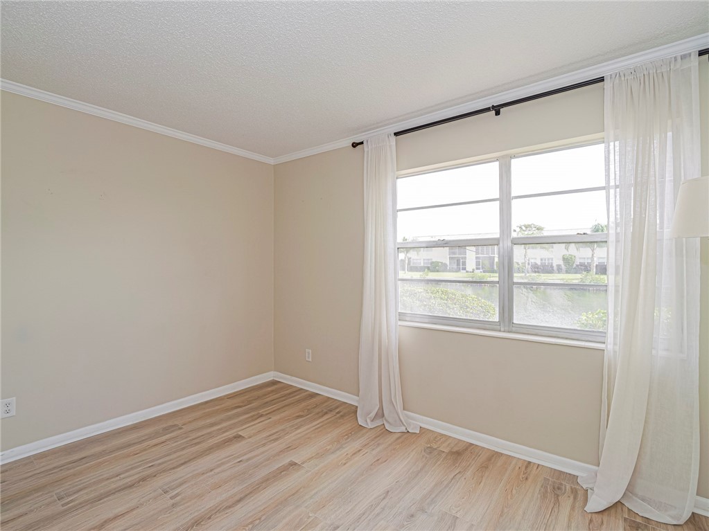 1860 Robalo Drive, Unit 105A Vero Beach, FL 32960 - Photo 17 of 35 a view of an empty room with wooden floor and a window