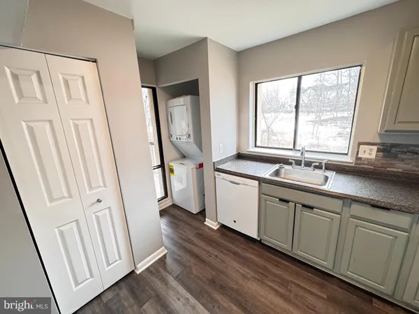 a large white kitchen with a sink a window and stainless steel appliances