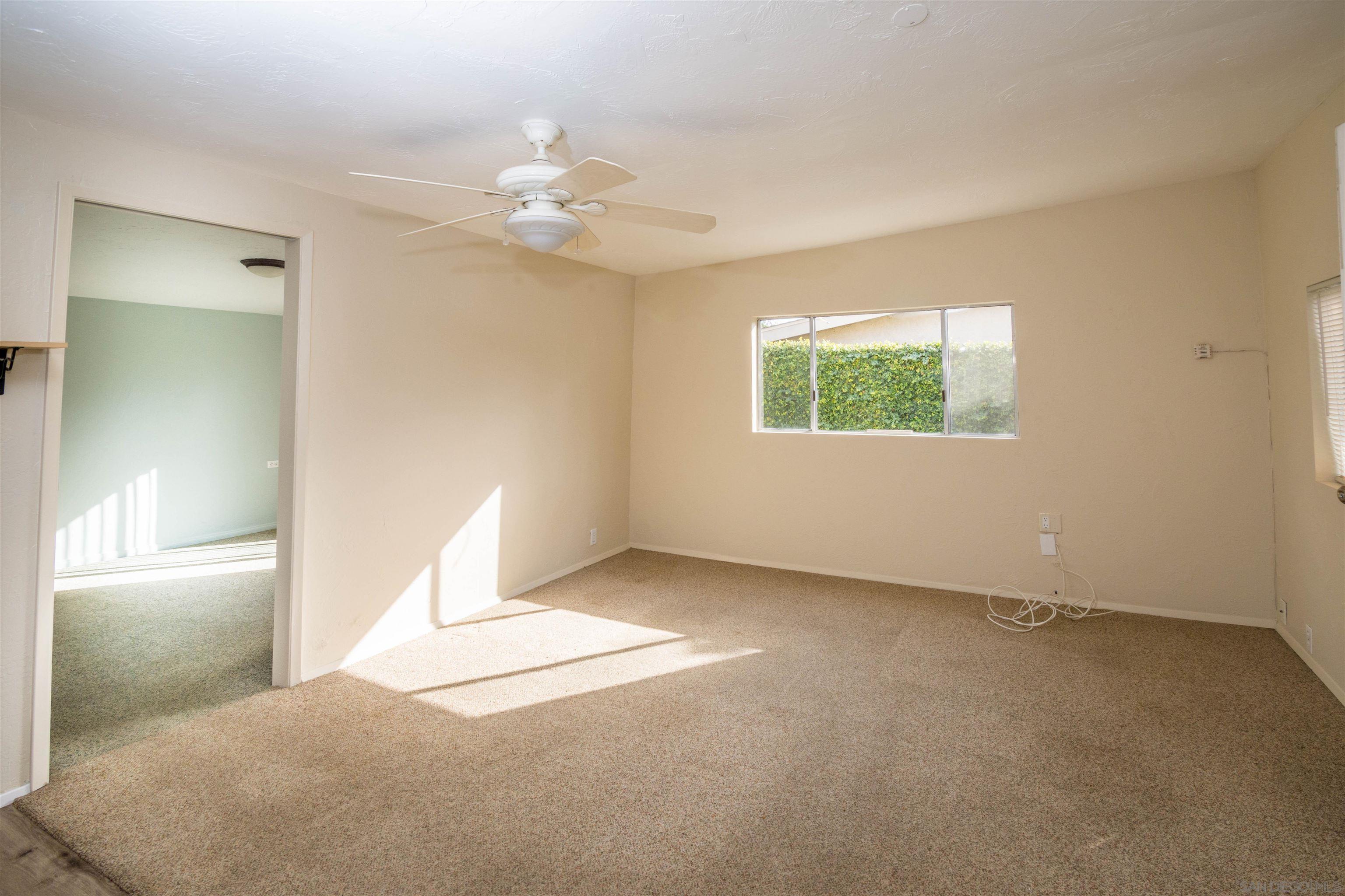 3218 Eureka Place, Unit B Carlsbad, CA 92008 - Photo 6 of 18 an empty room with windows and chandelier fan