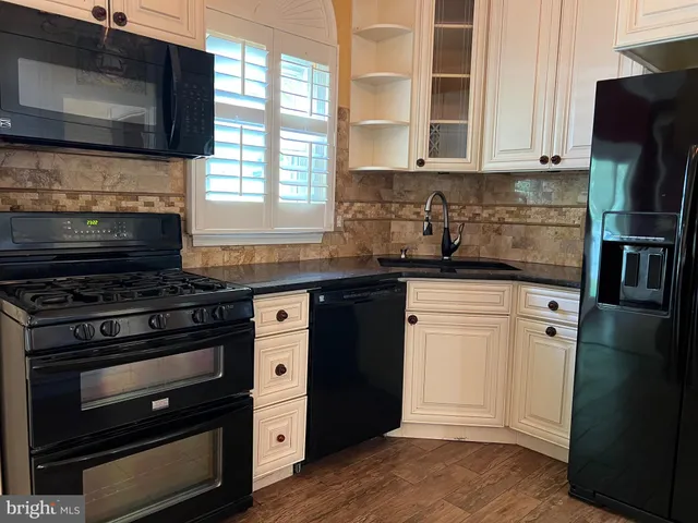 a kitchen with granite countertop a stove microwave and refrigerator
