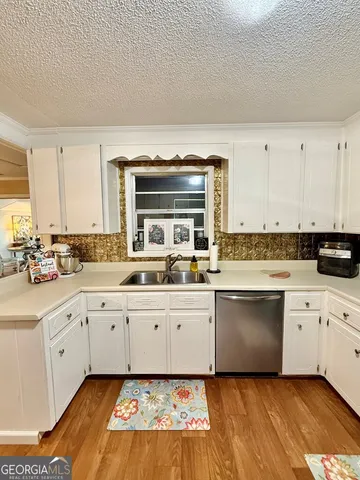 a large white kitchen with granite countertop a stove a sink and dishwasher with white cabinets
