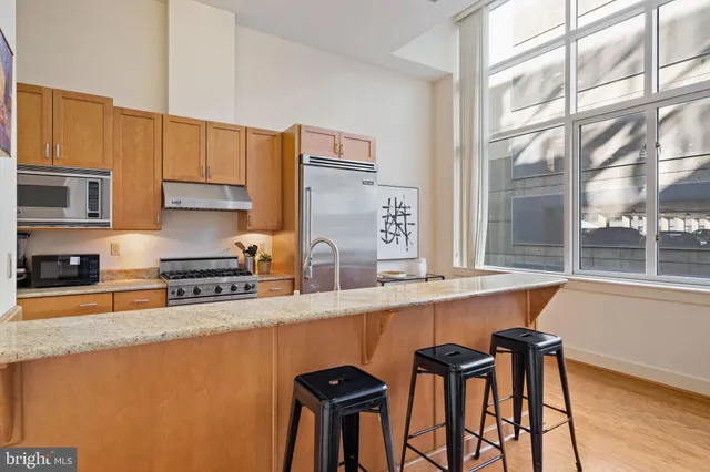 a kitchen with stainless steel appliances granite countertop a refrigerator a sink and a stove