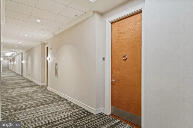 a view of a hallway with stainless steel appliances wooden floor and closet area