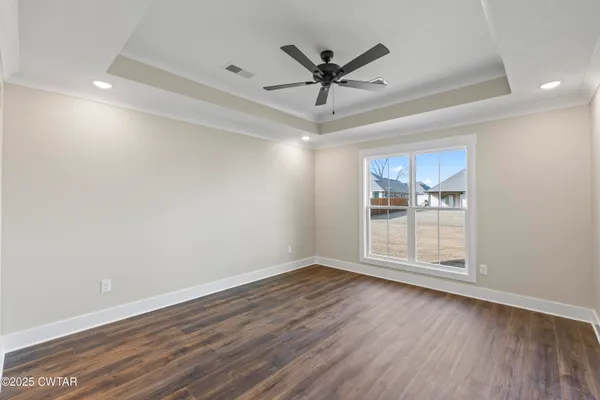 an empty room with wooden floor fan and windows