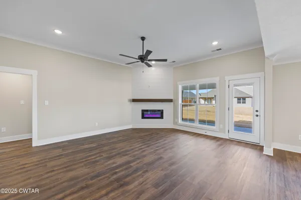 an empty room with wooden floor fireplace and windows