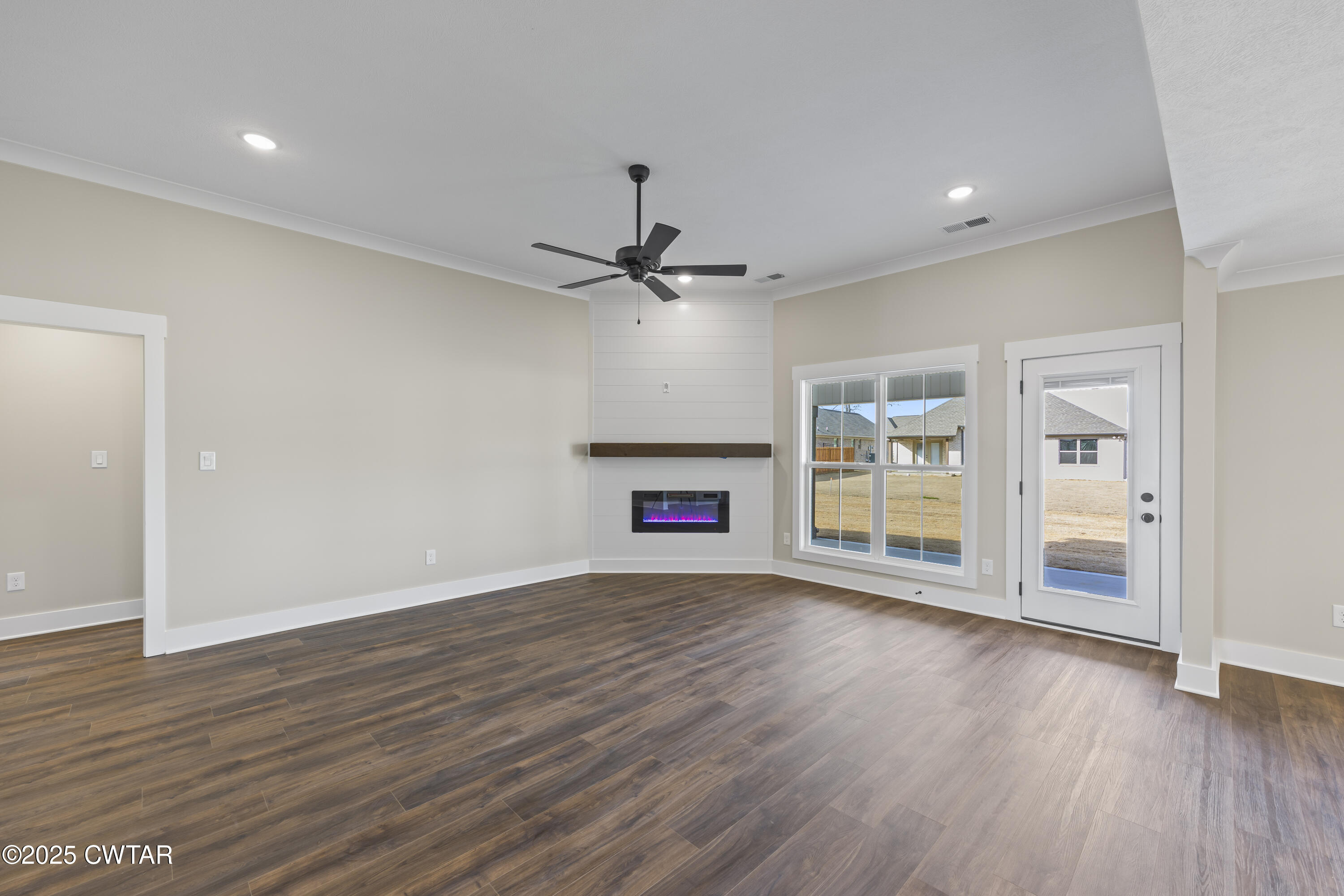 5 Easington Cove Jackson, TN 38305 - Photo 3 of 17 an empty room with wooden floor fireplace and windows