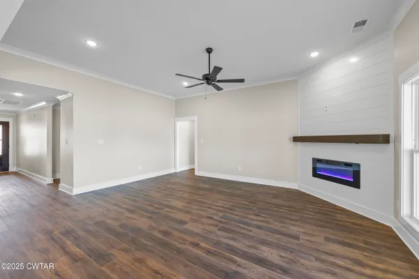 a view of an empty room with a ceiling fan and wooden floor