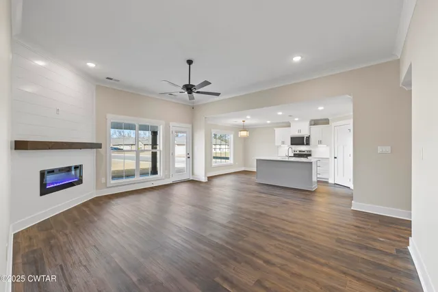 a view of an empty room and kitchen with wooden floor and a kitchen