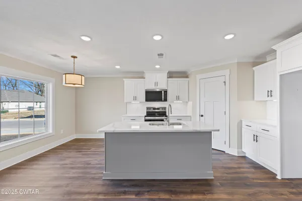 a large white kitchen with kitchen island a stove a refrigerator a sink dishwasher with a fireplace and wooden floor