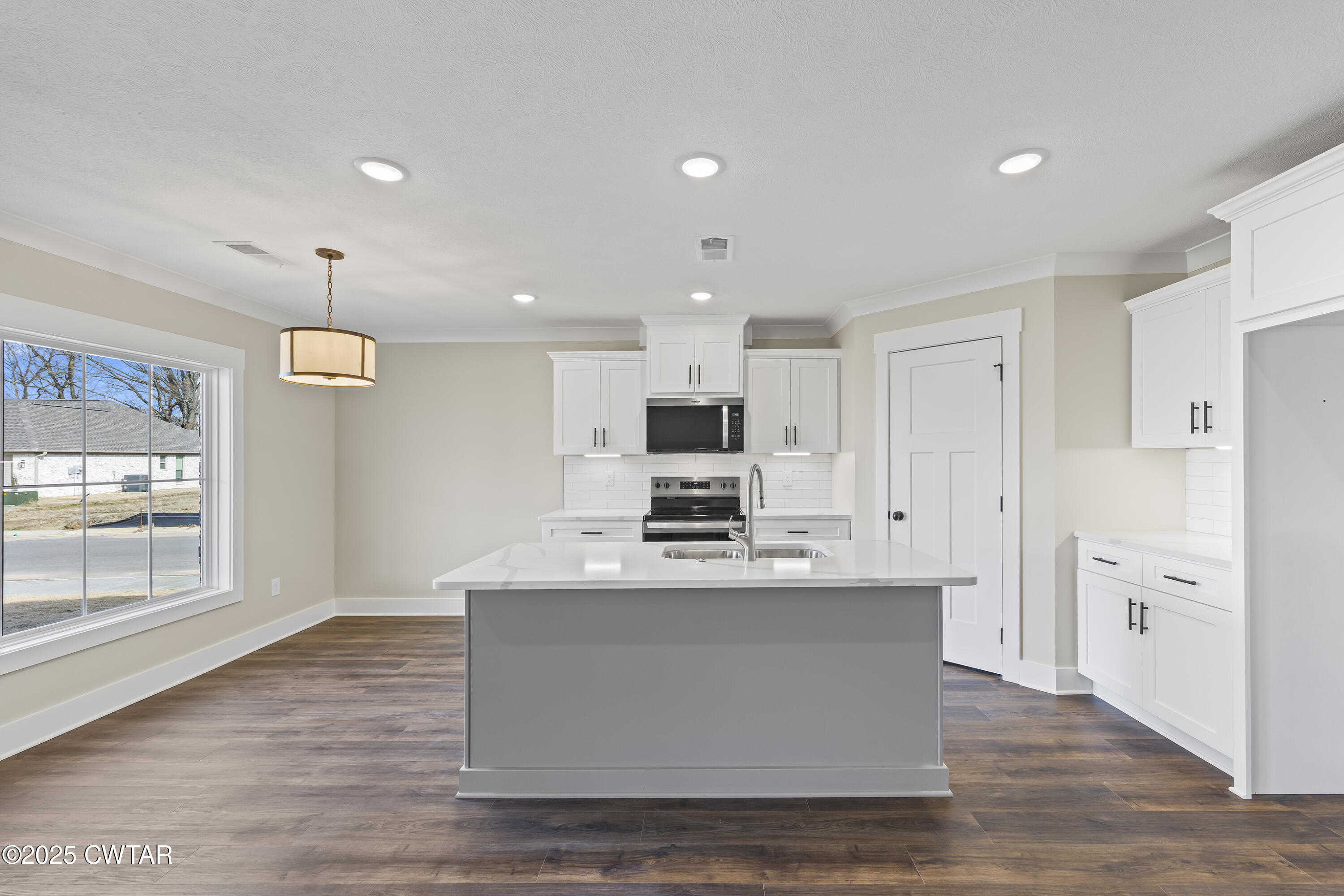 5 Easington Cove Jackson, TN 38305 - Photo 7 of 17 a large white kitchen with kitchen island a stove a refrigerator a sink dishwasher with a fireplace and wooden floor