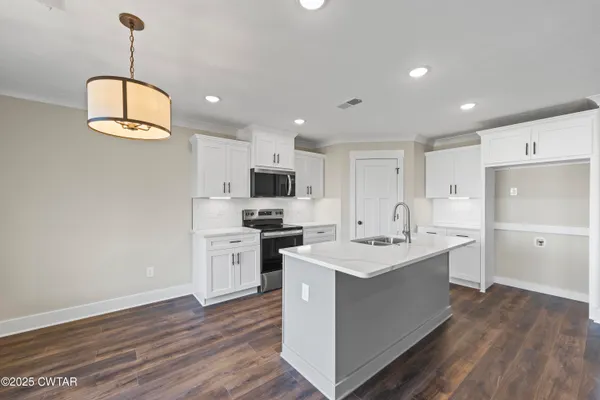 a kitchen with stainless steel appliances a stove a sink dishwasher a refrigerator white cabinets and wooden floor next to a window