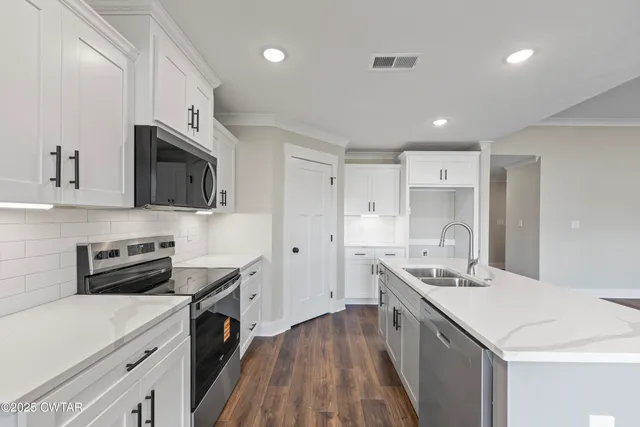 a kitchen with stainless steel appliances a sink stove top oven and cabinets