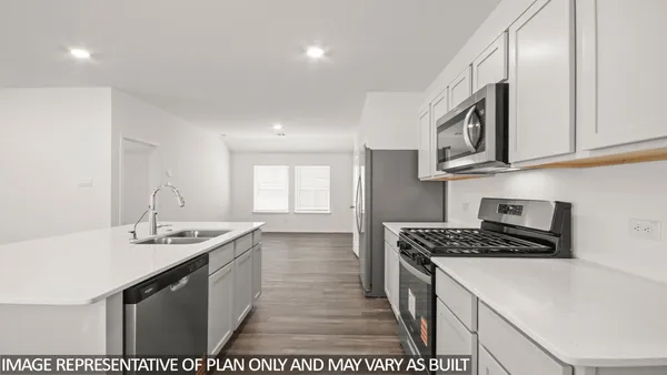 a kitchen with stainless steel appliances a stove top oven a sink a refrigerator with wooden floor