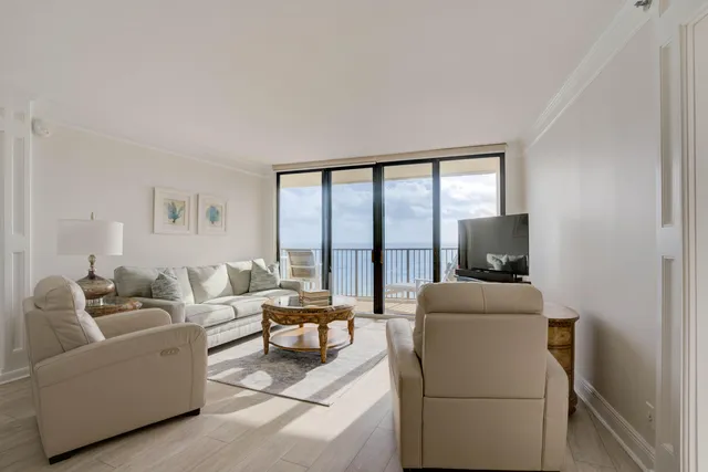 a living room with furniture a flat screen tv and a floor to ceiling window