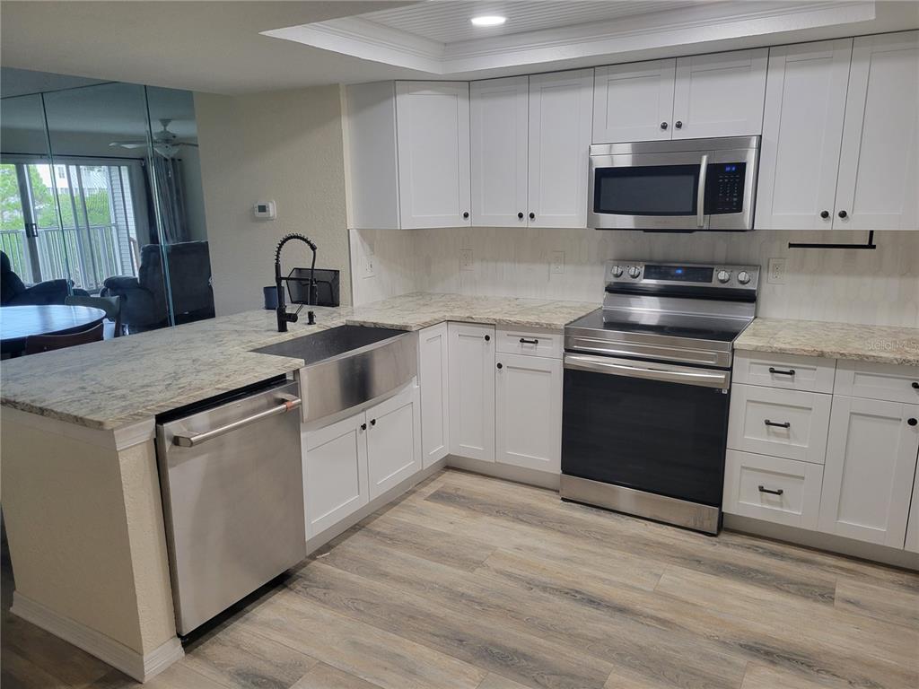 9976 Indian Key Trail, Unit 7 Seminole, FL 33776 - Photo 3 of 16 a kitchen with granite countertop a sink and a stove top oven