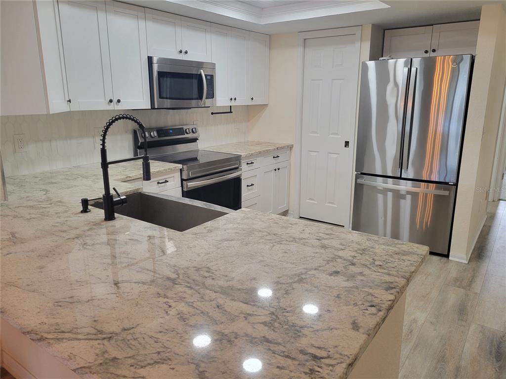 9976 Indian Key Trail, Unit 7 Seminole, FL 33776 - Photo 4 of 16 a kitchen with granite countertop a refrigerator sink and microwave