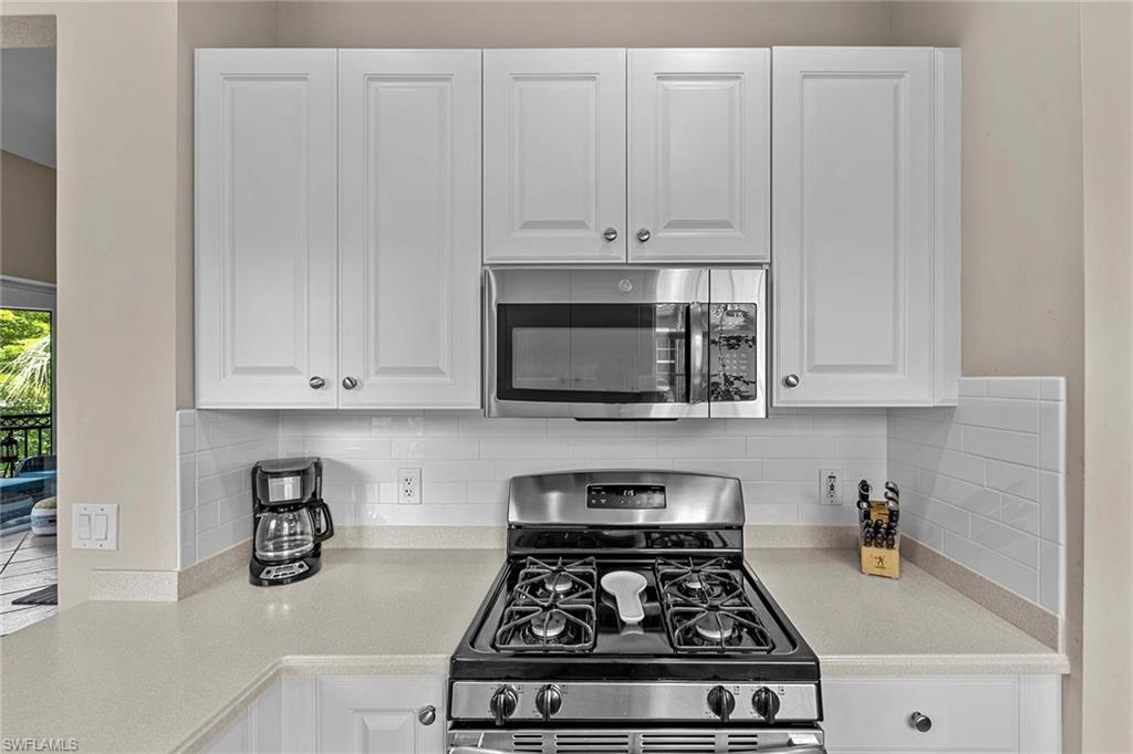 3975 Deer Crossing Court, Unit 201 Naples, FL 34114 - Photo 14 of 35 a kitchen with white cabinets and a stove top oven