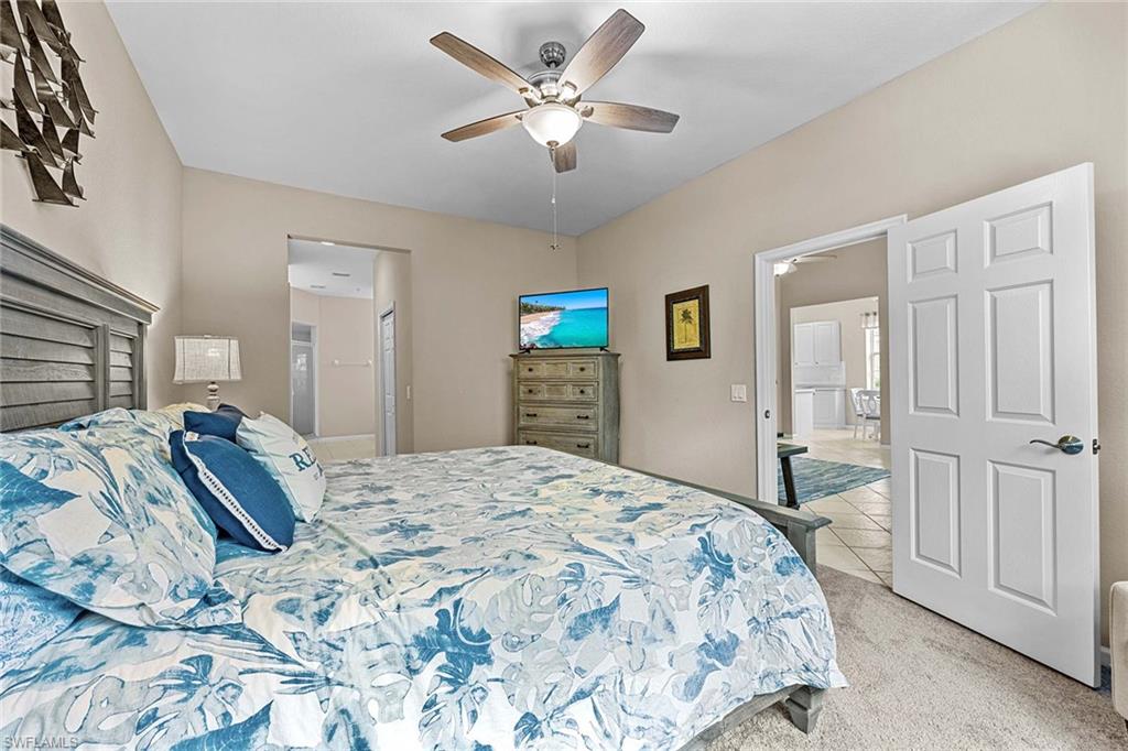 3975 Deer Crossing Court, Unit 201 Naples, FL 34114 - Photo 17 of 35 a spacious bedroom with a bed and a chandelier
