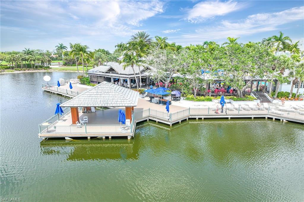 3975 Deer Crossing Court, Unit 201 Naples, FL 34114 - Photo 2 of 35 a small pool with lawn chairs and a table