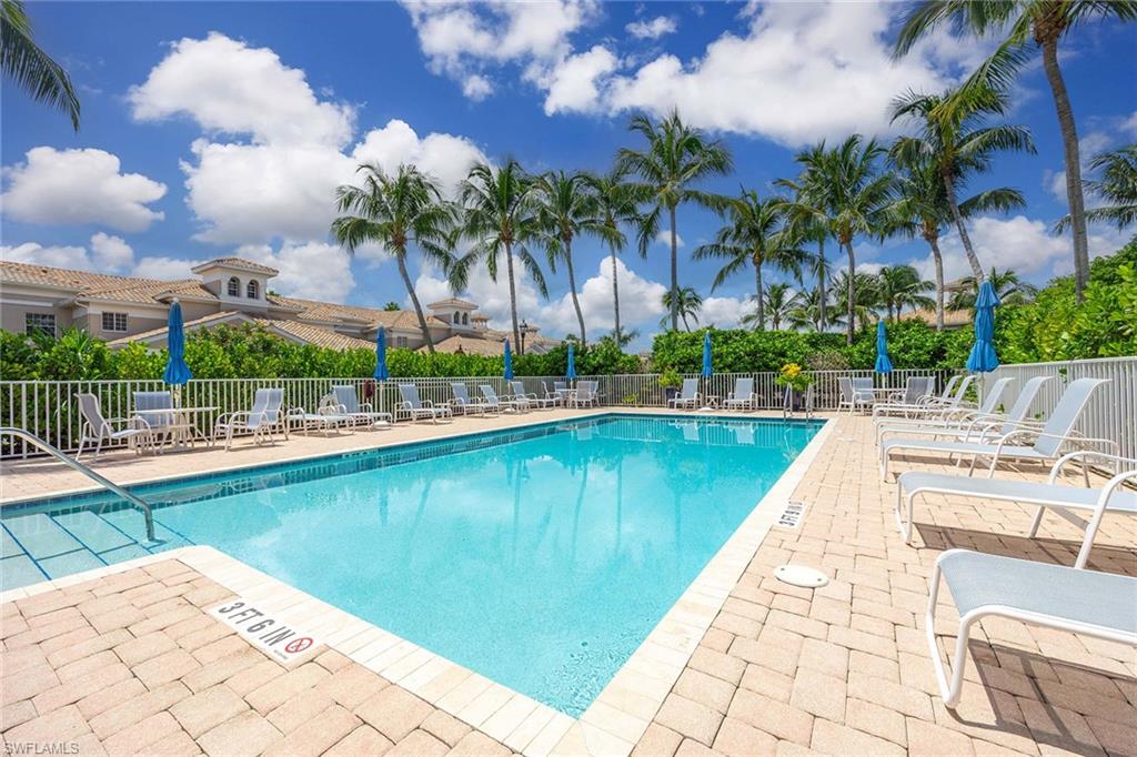 3975 Deer Crossing Court, Unit 201 Naples, FL 34114 - Photo 28 of 35 a view of swimming pool that has lawn chairs potted plants and palm trees