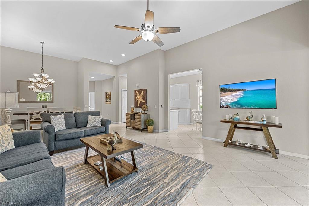 3975 Deer Crossing Court, Unit 201 Naples, FL 34114 - Photo 10 of 35 a living room with furniture a chandelier and a flat screen tv