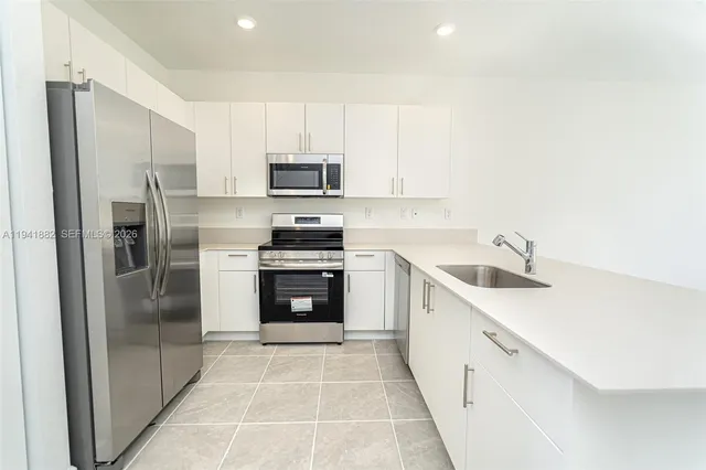 a view of kitchen with kitchen island a sink a stove and a refrigerator