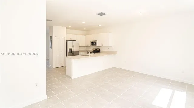 a view of kitchen with kitchen island white cabinets and stainless steel appliances