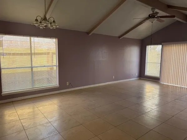 an empty room with windows and ceiling fan
