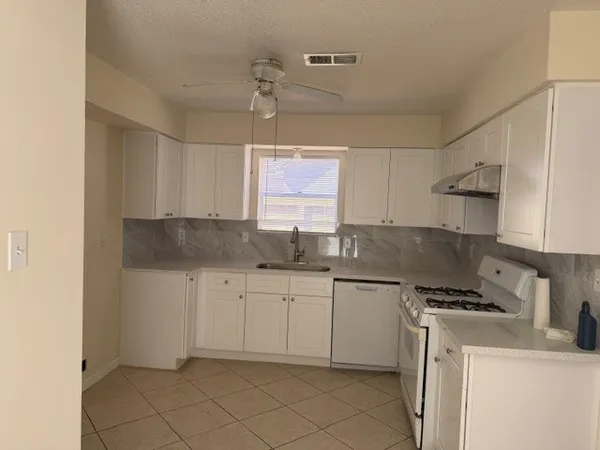 a kitchen with a sink white cabinets and white appliances