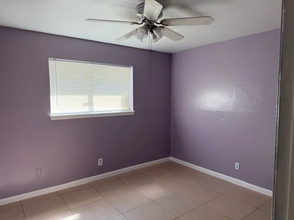 an empty room with a window and a fan