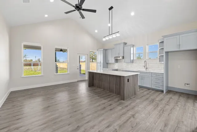 a large kitchen with stainless steel appliances a large counter top a sink a window and a refrigerator