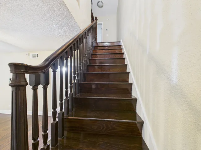 an empty room with wooden floor cabinet and windows
